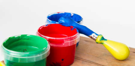 paint in small tubs with paint brush on wooden table