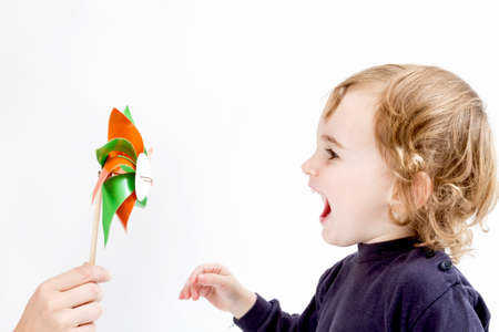 cute girl blowing to colorful windmill  studio shot in light grey background