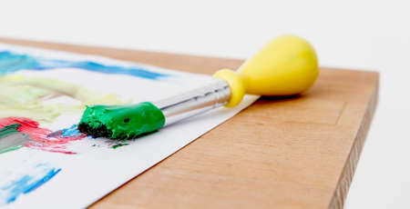 green paint with paint brush  and paper on wooden tableの写真素材