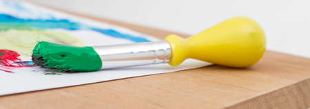 green paint with paint brush  and paper on wooden tableの写真素材