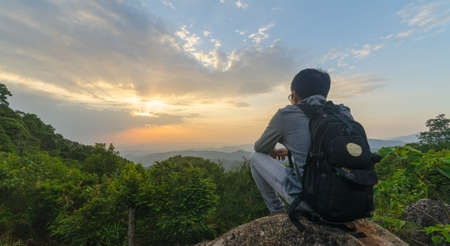 Freedom traveler sitting on rock and enjoy a beautiful nature. Image with sunset and sunrise timeの写真素材