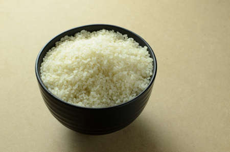 Japanese rice in a black bowl on backdropの写真素材