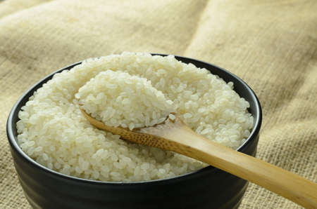 Japanese rice in a black bowl on backdrop,wooden spoon  scooping riceの写真素材
