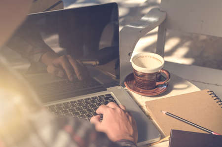 working on laptop, close up of hands of business man,coffee cup,notebook on tableの写真素材