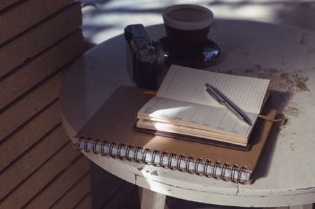A pen  put on notebook and the camera near coffee cupの写真素材