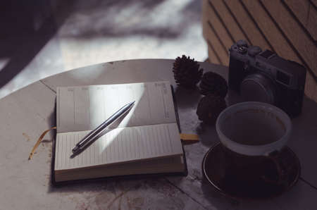 A pen  put on notebook and the camera near coffee cupの写真素材