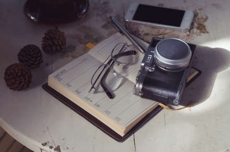 Glasses and camera put on notebook in the deskの写真素材