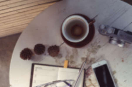 A pen  put on notebook and the camera near coffee cup blur backgroundの写真素材