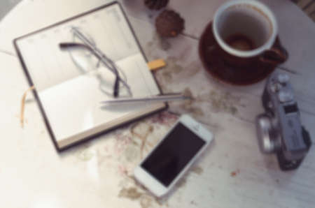 A pen  put on notebook and the camera near coffee cup blur backgroundの写真素材