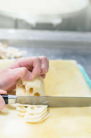 Chef cutting lotus root with skillfully and cutting fastの写真素材