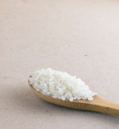 Rice in wooden spoon on backgroundの写真素材