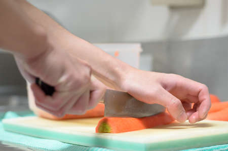Chef working cutting carrot on cuttingboardの写真素材