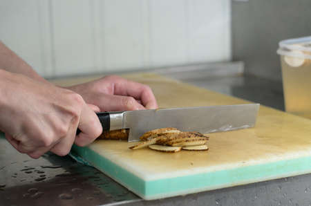 Chef working cutting root vegetable on cuttingboardの写真素材