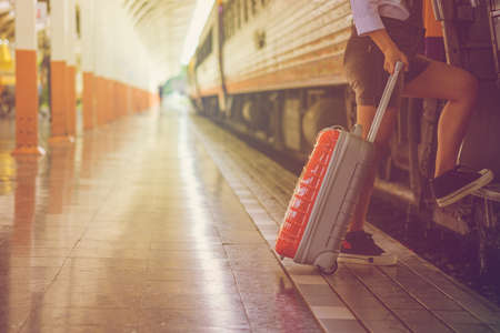 Woman hand  drag suitcase red color go to travel,her going on the train at asian,effect vintageの写真素材