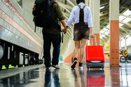 Woman and man hold hands walk in train station go travel drag bag red color,blur background,の写真素材