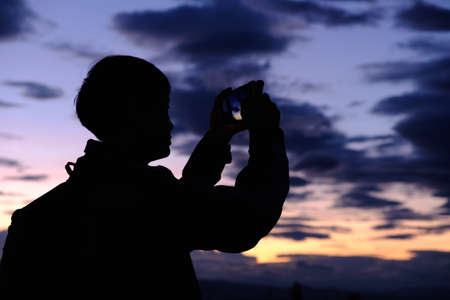 silhouette man taking photos  with mobile phoneの写真素材