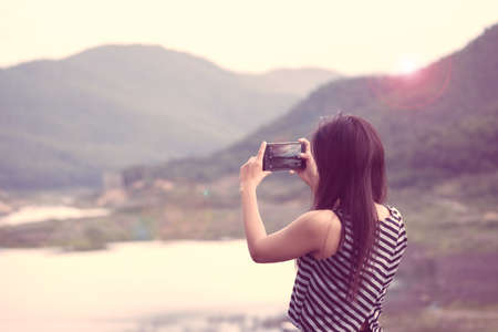 Female traveler photographing mountains at asia,lens flare effect and vintage toneの写真素材
