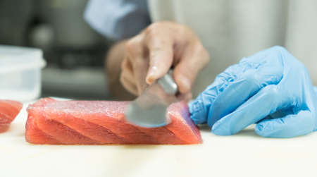 Chef cutting tuna fish with knife on boardの写真素材