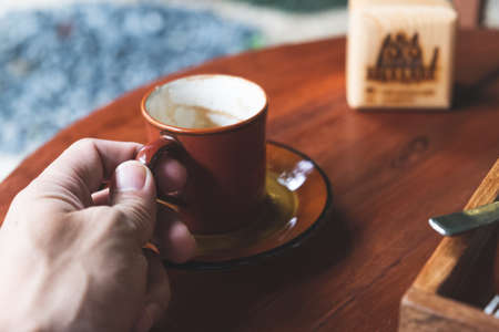 cup of coffee in hand on the wooden tableの写真素材
