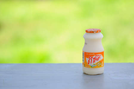 CHIANGRAI,THAILAND-SEPTEMBER 7,2019:  Milk Put on a wooden floor and green color blur background with copy spaceのeditorial素材