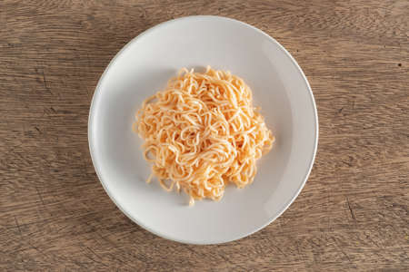 The noodles are in a round white plate placed on a wooden tableの写真素材