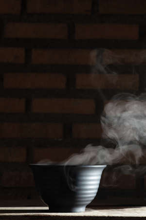Soup hot in black bowl on wooden table, food steam and copy space selective focusの写真素材