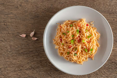 The noodles are in a round white plate placed on a wooden table.copy spaceの写真素材