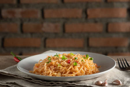 The noodles are in a round white plate placed on a wooden table.noodle concept with copy spaceの写真素材