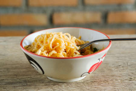 A cup of instant noodles placed on a wooden table With chilli as ingredientsの写真素材