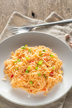 The noodles are in a round white plate placed on a wooden table.noodle concept with copy spaceの写真素材