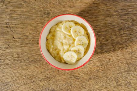 Mashed bananas in bowl on wooden backdropの写真素材