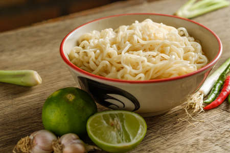 A cup of instant noodles placed on a wooden table With limeの写真素材