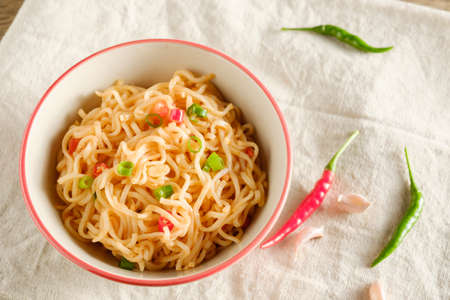 A cup of instant noodles placed on a wooden table With chilli as ingredients ,top view noodleの写真素材