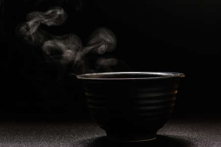 Soup hot in black bowl on wooden table,food steam and copy space ,selective focus.Fresh foods conceptの写真素材