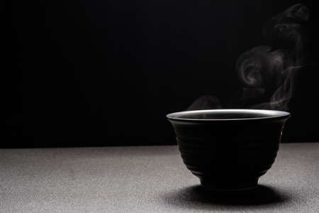 Soup hot in black bowl on wooden table,food steam and copy space ,selective focus.Fresh foods conceptの写真素材