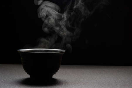 Soup hot in black bowl on wooden table,food steam and copy space ,selective focus.Fresh foods conceptの写真素材