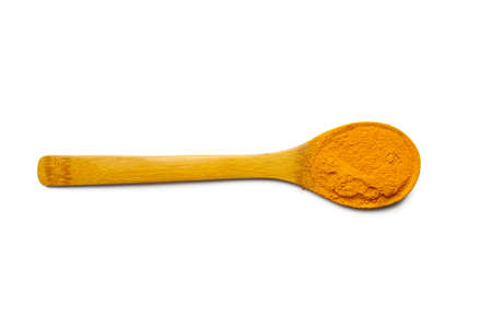 Dry turmeric powder and wooden spoon on  isolated whiteの写真素材