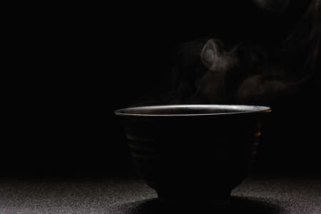 Soup hot in black bowl on wooden table,food steam and copy space selective focus.Fresh foods conceptの写真素材