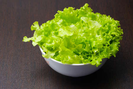 Green lettuce in white bowl on wooden backgroundの写真素材