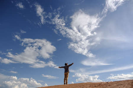 Man stretching out his arms on grounds.Asian men wear gray shirts, brown pants are standing outdoors.Look at the copy space.Wear a hat and scarf.Man standing on the ground.の写真素材