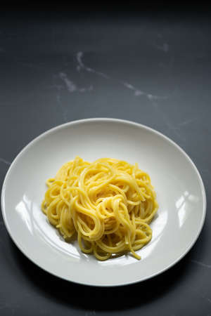 The noodles are in a round white plate placed on table.yellow noodle.top view food and copy space.