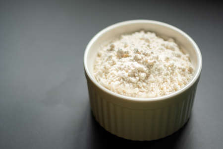 Bowl of flour on dark backdrop.Flour in ceramic cup.Starch cup with copy space