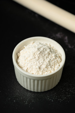 Bowl of flour on dark backdrop.Flour in ceramic cup.Starch cup with copy space.の写真素材