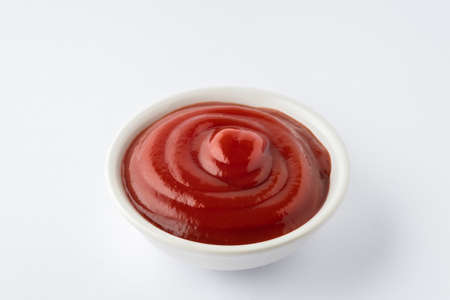 Tomato ketchup in ceramic bowl on white background.の写真素材