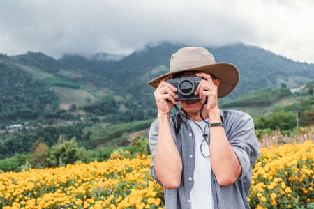 Asian man holding a camera with both hands.man wearing a hat taking pictures,copy spaceの写真素材