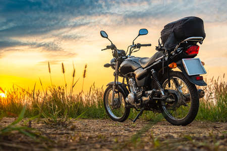 Black retro motorcycle with backpack parked outdoors.Classic motorcycle and beautiful blue sky in the eveningの写真素材
