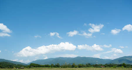 The white clouds have a quaint and rural shape. The sky is cloudy and blue.の写真素材