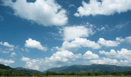The white clouds have a quaint and rural shape. The sky is cloudy and blue.の写真素材