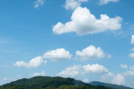 The white clouds have a strange shape and moutain.The sky and the open space have mountains below.Clouds floating above the mountainsの写真素材