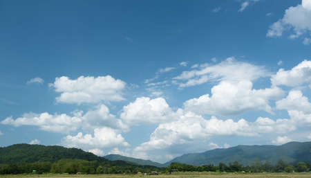 The white clouds have a quaint and rural shape. The sky is cloudy and blue.の写真素材